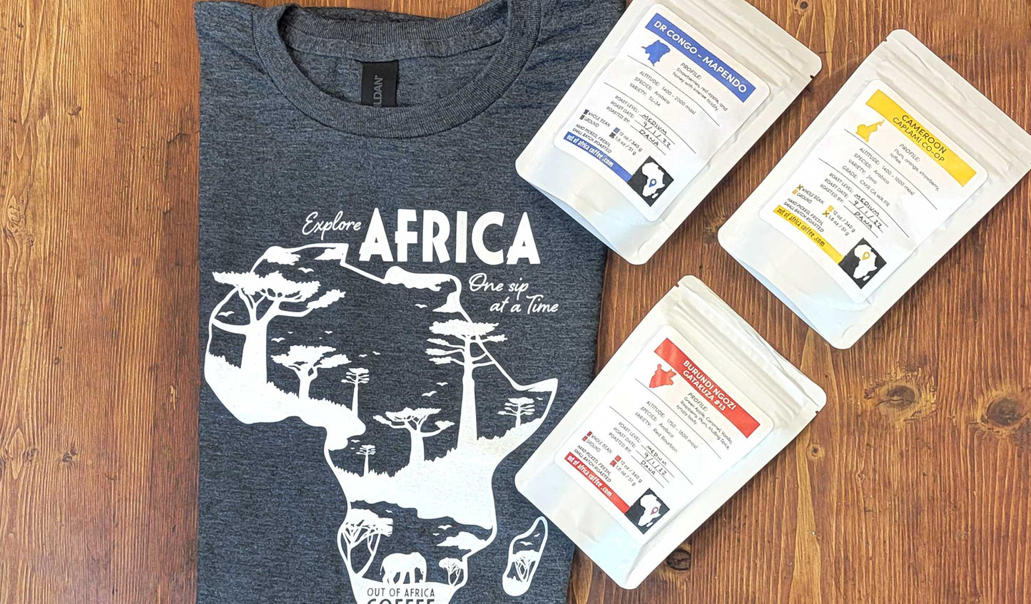 Heathered Grey T-Shirt with "Explore Africa One Sip at a Time" in white with African continent on the front shown with 3 1.8oz bags of coffee